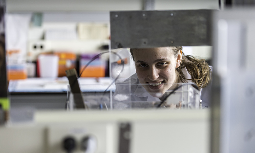 A student in a lab looking at the camera across a table.