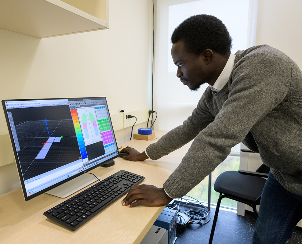 A student leaning over a desk working on a computer with data on the screen.