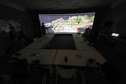 A dark room with a bright display screen on one end.
