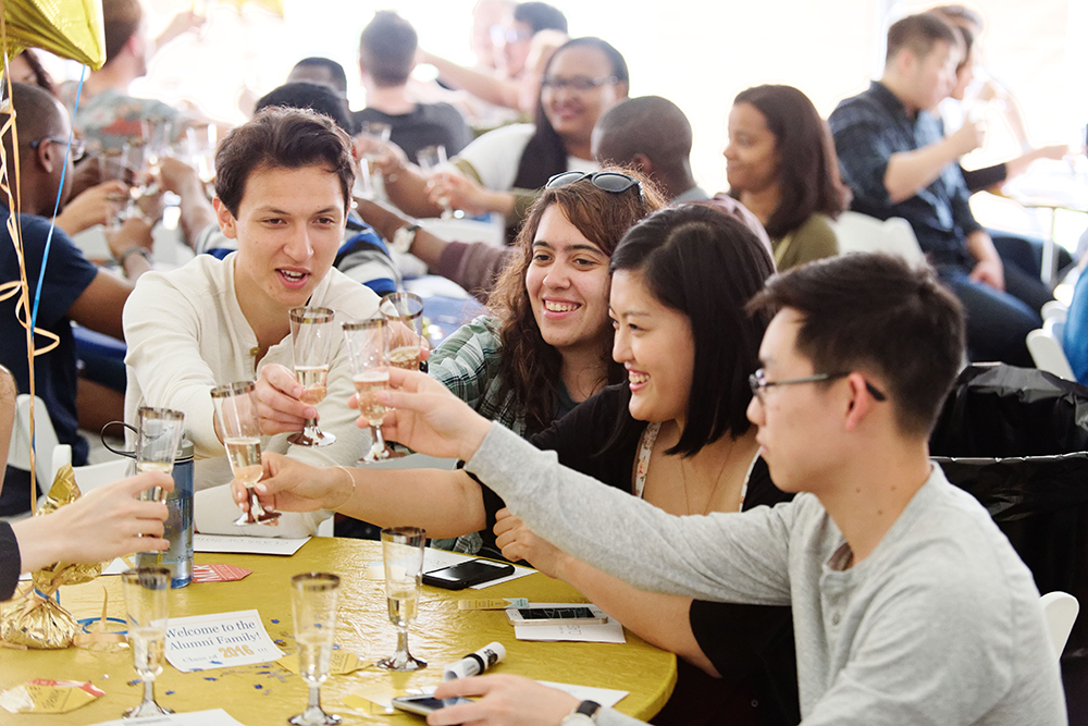 A group of seniors sitting at a table raise their glasses to toast.