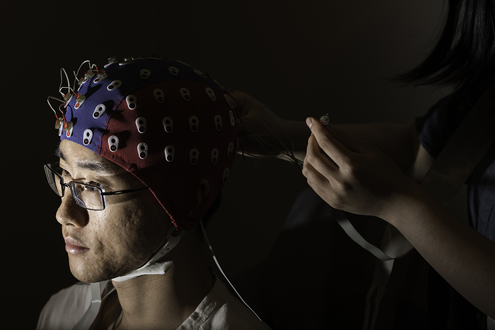 A biomedical engineering student adjusts an electroencephalography cap on a fellow lab member.
