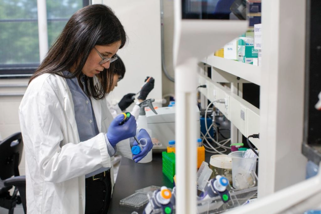 A student wearing a lab coat in a lab.