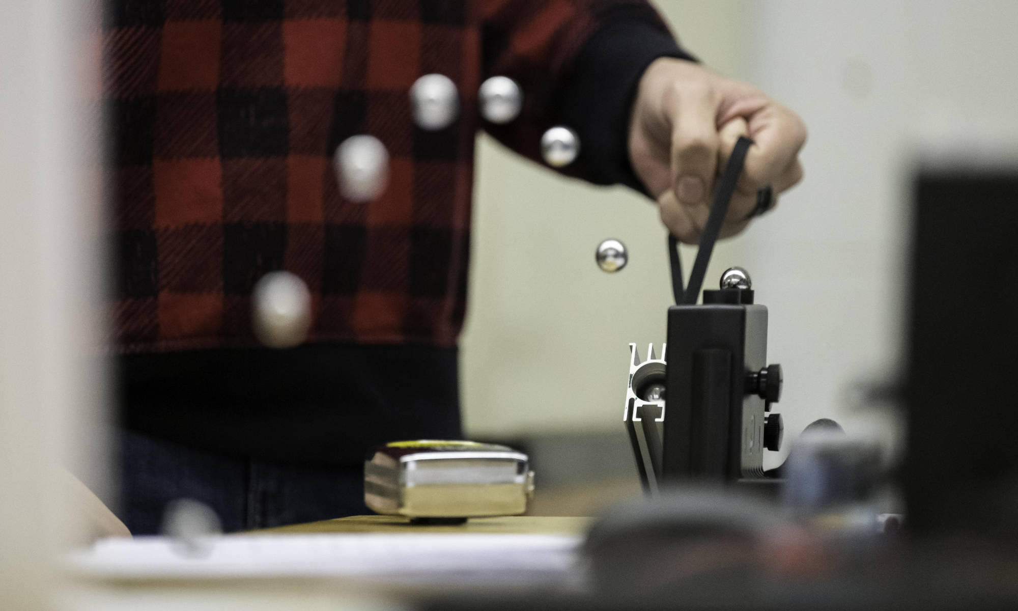 Composite photo of a metal ball shot through a spring-loaded launcher during mechanical engineering class and lab.