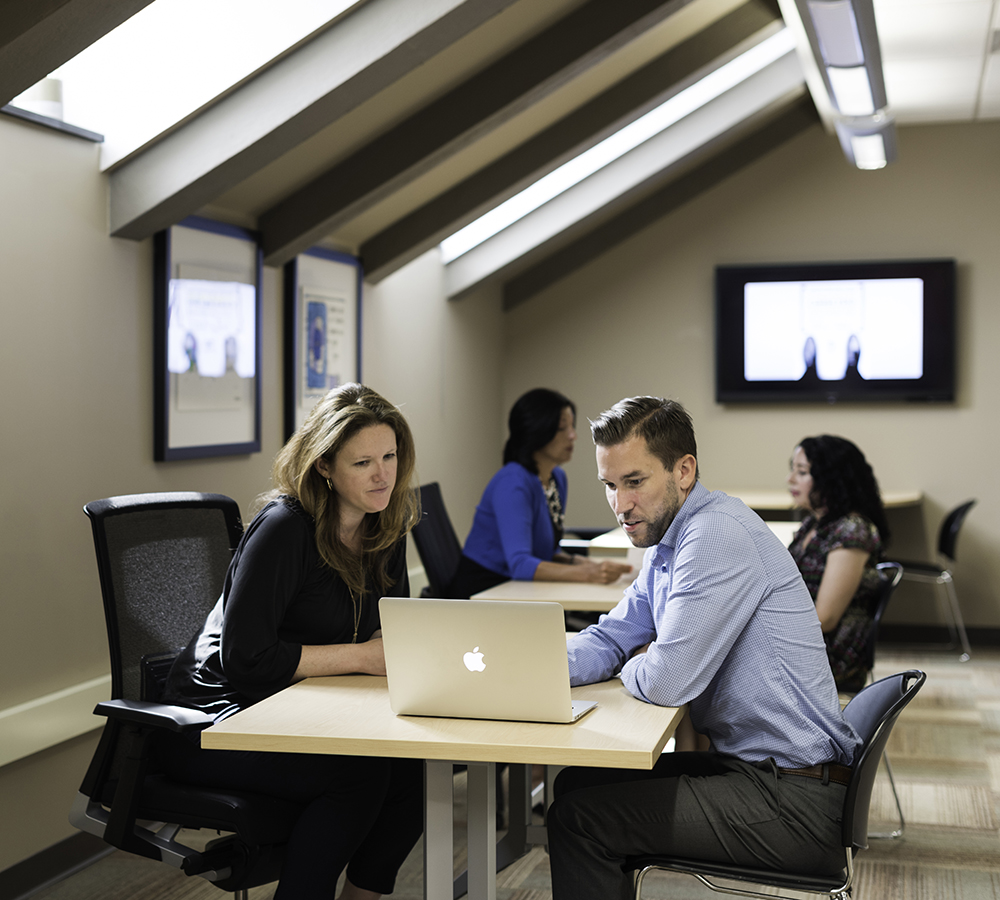 An advisor sitting at a laptop with a student.