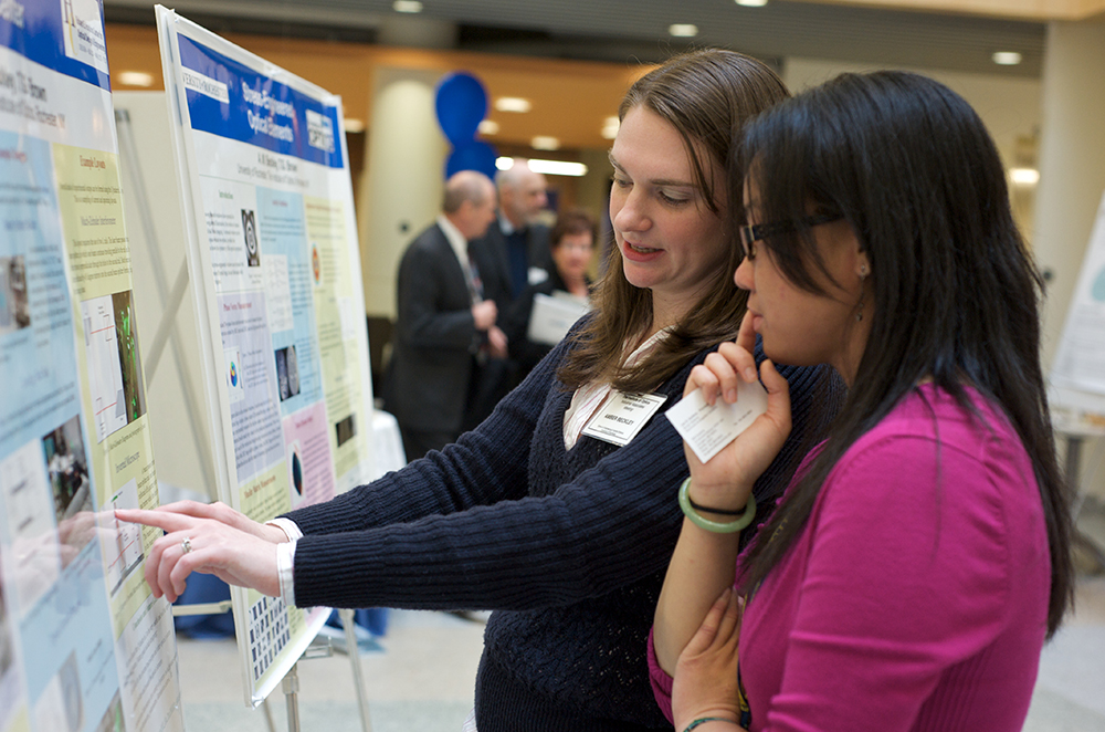 Two people discussing a presentation at a poster session.