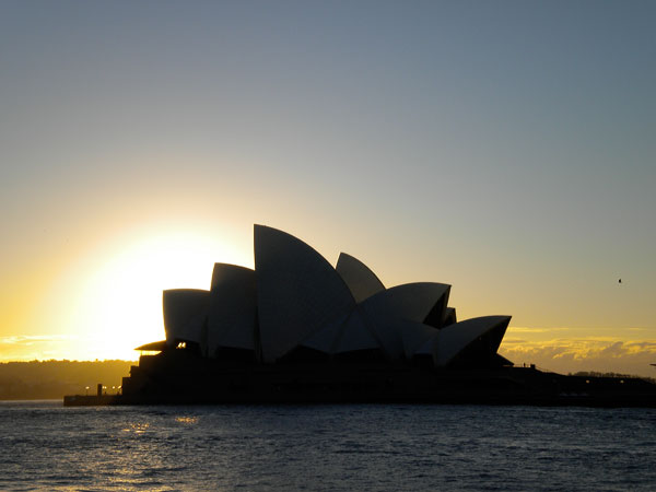 A view of the Sydney Opera House as seen from the water at sunset.