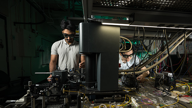 Two students working with equipment in a lab.