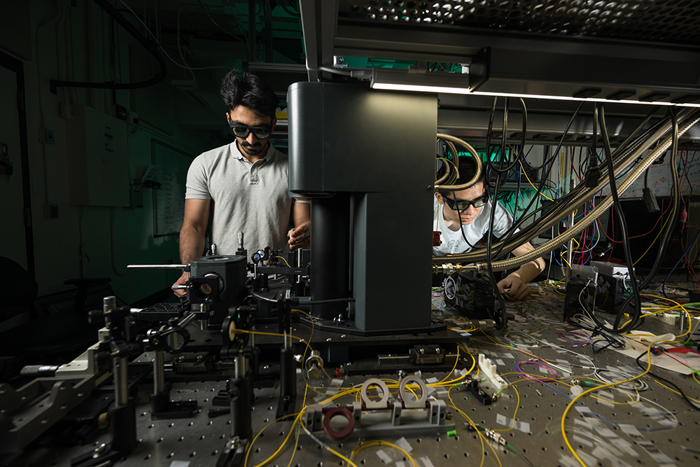 Two students working with equipment in a darkened lab.