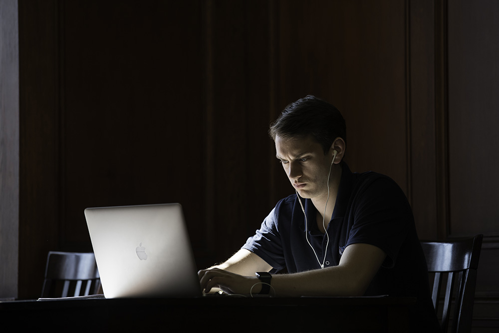 Morning light shines on a person sitting at a table with a laptop.