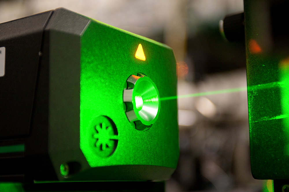 A green laser beam shoots from a machine.