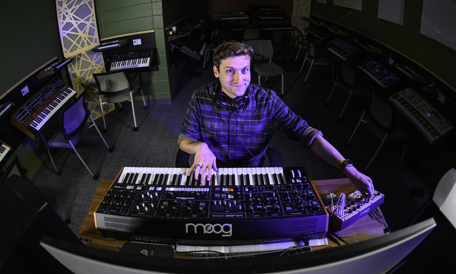 Rick Carl sitting in front of a Moog Synthesizer in the University of Rochester's synthesizer lab.