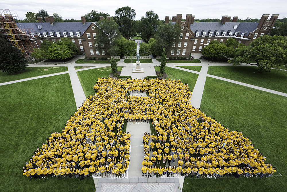 Students from the class of 2023 as seen from above all wearing a yellow shirt and forming a giant R on the quad.