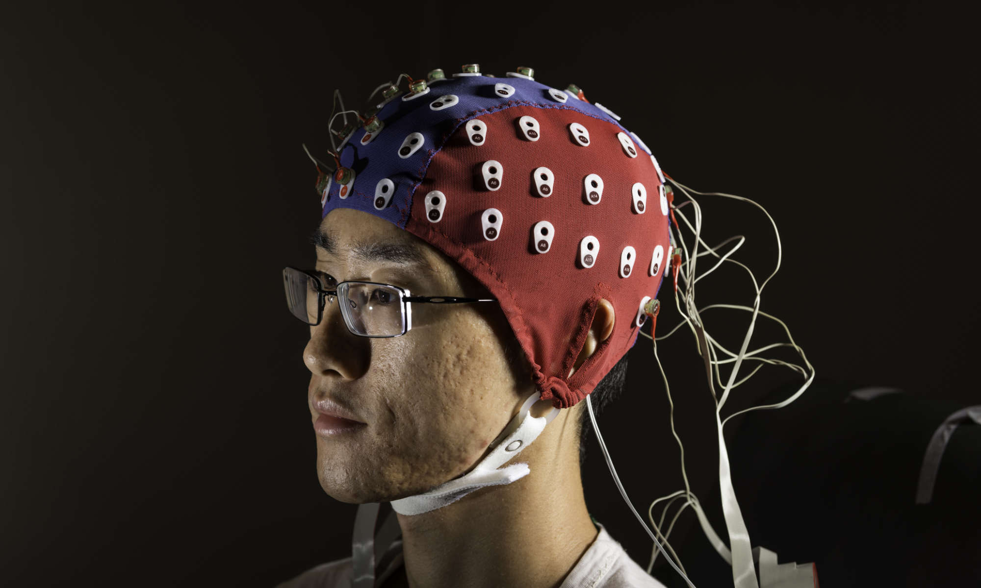 Close up of a person staring off camera while wearing an EEG cap.