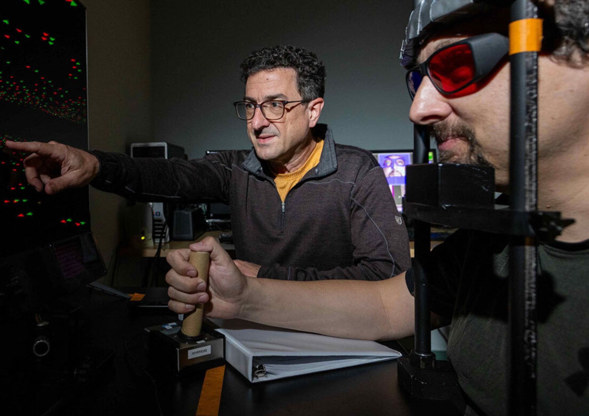 EYES ON THE PRIZE: Professor Greg DeAngelis (left) looks on as postdoctoral fellow Vitaly Lerner performs a virtual reality task investigating how eye movements help the brain interpret 3D space. (University of Rochester photo / John Schlia)