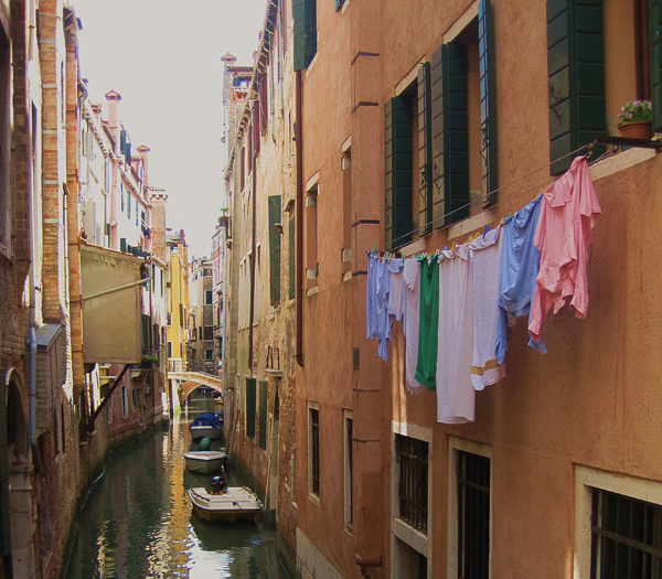 A canal full of water between two buildings with bridges in the background.