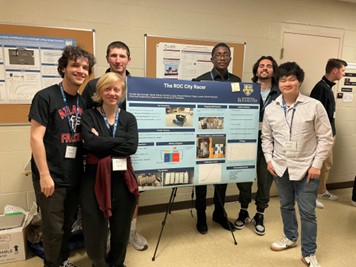 A group photo of the team standing with their poster presentation.