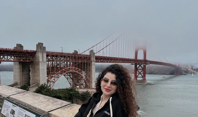 Woman smiling at camera with Golden Gate Bridge and clouds in background