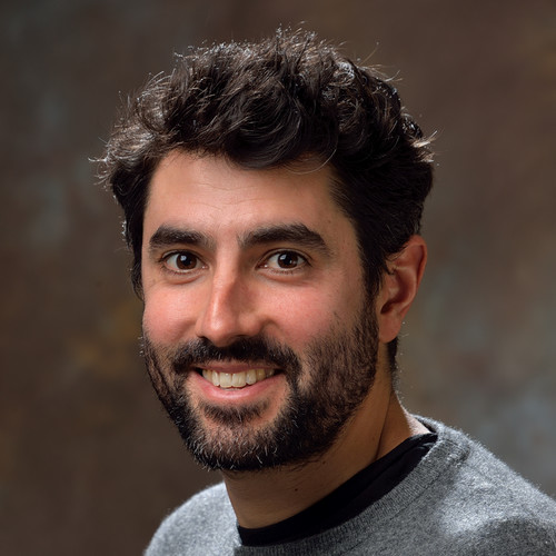 Man smiling at camera wearing grey sweater