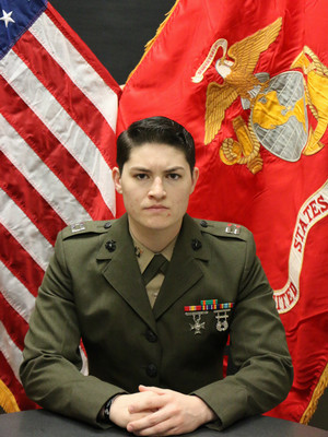 First Lieutenant Merino sitting in front of the American flag.