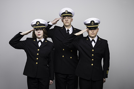 A portrait of three recruits in their dress uniforms saluting the camera.