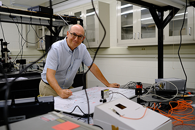 Postigo standing with some equipment while smiling at the camera.