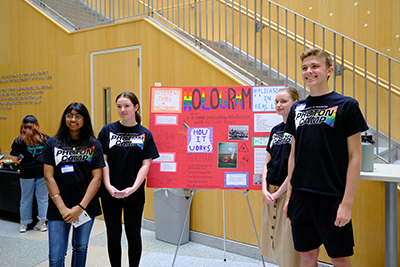 Three photon camp students standing with their poster presentation.